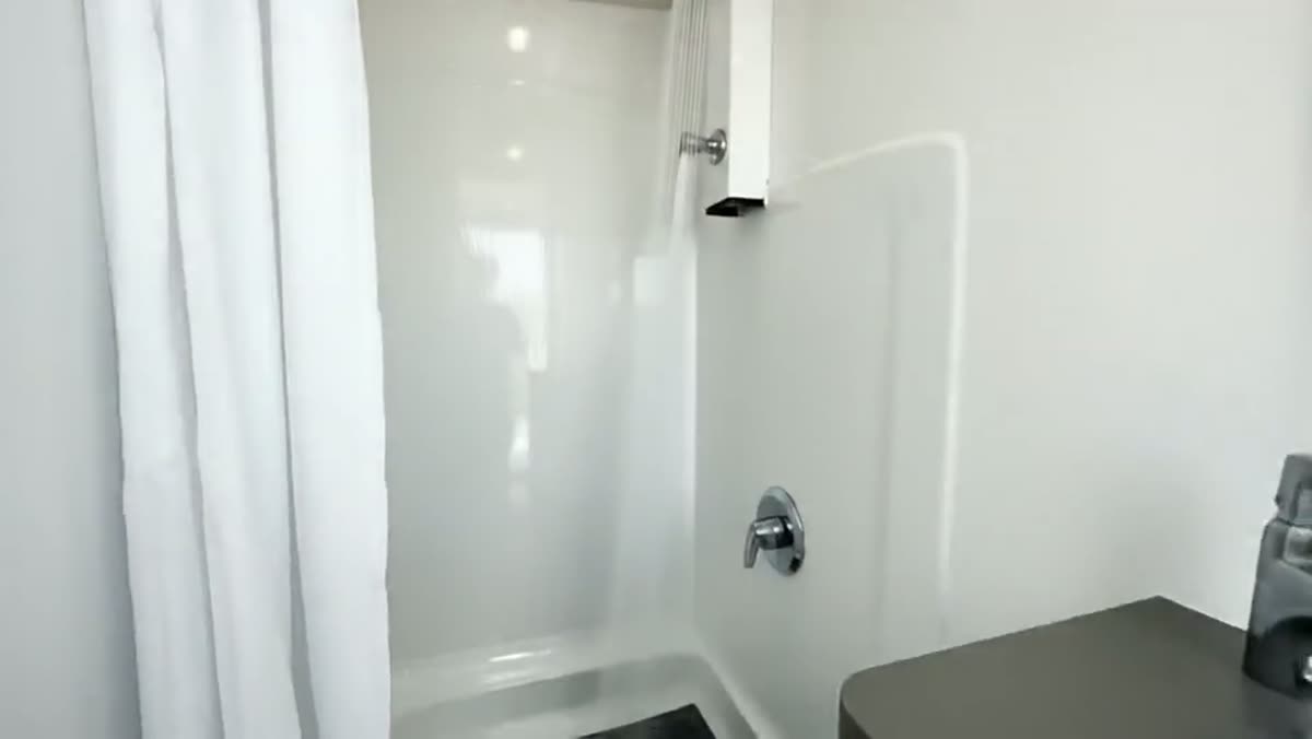 Inside a shower trailer, showing a private stall, tile finish, vanity and bright interior lighting